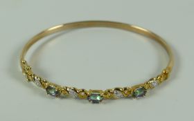 A MODERN BLUE 9k YELLOW GOLD GEMSTONE BANGLE, 5.5gms