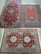 THREE SMALL RED GROUND WOVEN WOOLLEN EASTERN CARPETS, all having bordered edges and tasselled