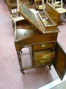 AN EDWARDIAN MAHOGANY DAVENPORT, the lift up top shelf with carved gallery detail opening to