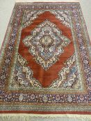 A RUST GROUND EASTERN WOVEN CARPET with spandrel and cartouche decorated centre with a multi-