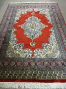 AN EXCELLENT EASTERN WOVEN WOOLLEN CARPET with rich red ground central cartouche and triple bordered