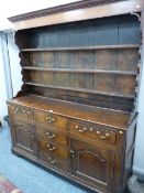 A GEORGE III OAK & PINE DRESSER, the three shelf wide boarded back plate rack with shaped sides on a