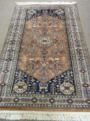 AN EASTERN WOOLLEN WOVEN CARPET on a rust and blue ground having repeating traditional designs