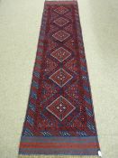 A MESHWANI RUNNER, red ground with chevron border and repeating diamond central pattern, 267 x 66
