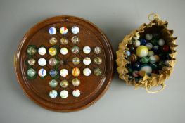 A VINTAGE WOODEN SOLITAIRE BOARD on squat bun feet with seventy eight ribbon core swirl and other