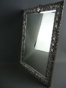 A LARGE EMBOSSED SILVER DRESSING TABLE MIRROR, rectangular with bevelled edged glass and easel