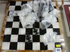 Carved stone chess set on an onyx and possibly granite chess board