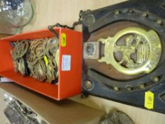 Quantity of vintage horse brasses, one with horseshoe on an oak display