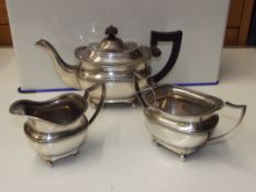 Silver three piece tea service comprising teapot, cream jug, and sugar bowl, raised handles,