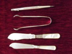 Two butter knifes, sugar tongs together with silve
