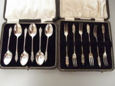 Two cased sets of silver apostle forks and spoons