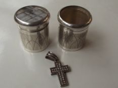 Two white metal beakers together with a cross pend