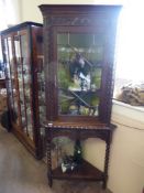 A Stained Oak Glazed Fronted Corner Cupboard, with two scalloped shelves, raised on carved bobbin