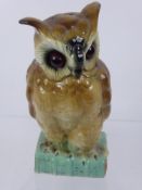 A Porcelain Brown Owl with Glass Eyes, resting on a book entitled 