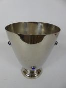 An Arts and Crafts Silver Plated Vase, having blue cabachon stone decorations, approx 23 cms high.