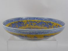 A Contemporary Blue and Yellow Chinese Ceramic Bowl, depicting chasing dragons, marks to base,