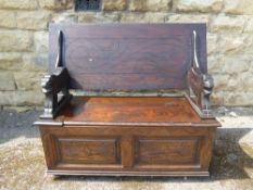 A Carved Mahogany Monk's Bench, with lion supports, storage cupboard beneath, label reads 