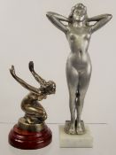 A White-Metal Bonnet Ornament, in the form of a crouching feminine nude,raised on a stepped mahogany