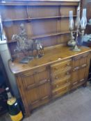 An Ercol Light Oak Dresser, with two plate shelves, four drawers and a cupboard to either side,