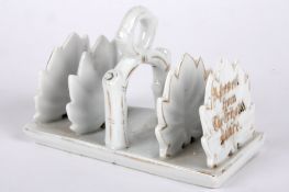 A porcelain toast rack 'A Present from The Crystal Palace' modelled as leaves highlighted in gilt