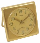 A 1950s gilt metal 8-day travel clock by Hermes with easel stand, and dial with Arabic numerals,