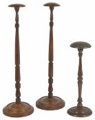 A pair of Georgian walnut and mahogany wig stands of turned columnar form with domed circular top,