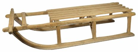 A vintage pine sledge with slatted seat upon turned supports with metal runners width 26.5 x 117 x