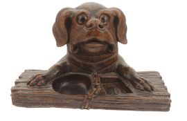 A dogs head inkwell desk stand, 20th century modelled as a dogs head and paws resting upon a plank