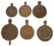 Six carved treen butter moulds, 19th century and later each of circular form with pierced handle and