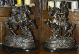 A pair of large early 20th century Spelter figures of warriors on horseback each on ebonised oval