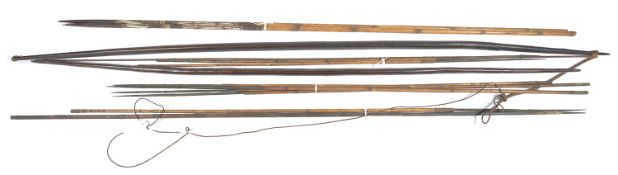 A collection of African tribal arrows and bows, the two bows of tapering form with pointed ends, one