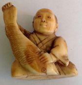 A small ivory Japanese okimono figure the realistically carved figure of seated gentleman holding
