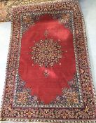 An early 20th century Persian carpet, the quartered madder field with central floral medallion