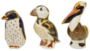 A group of three Royal Crown Derby paperweights the first modelled as a brown pelican, the second
