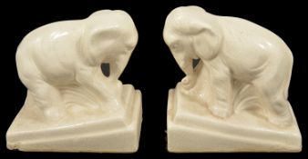 A pair of porcelain glazed elephants, 20th century modelled standing upon rectangular sloped