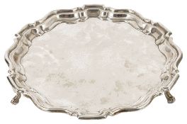 An Edwardian silver salver, London 1904with pie crust stepped edge raised upon three scrolled