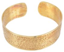 A wide Continental yellow metal engraved cuff bangledecorated with flower posies on a plannished