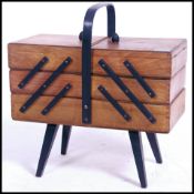A 1950's mid century metamorphic sewing box with central handle over sectional outward moving body