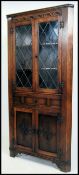 A Jaycee style Jacobean revival corner cupboard having leaded glass doors over carved doors beneath.