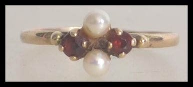 A 9ct / 375 gold ruby garnet stone and seed pearl ladies ring. The ring with twin seed pearls