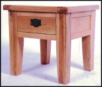 A contemporary solid chunky oak coffee table having a single drawer to the front, raised on square