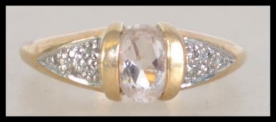 A hallmarked 9ct gold ring with central clear oval cut gemstone with illusion set diamond chip