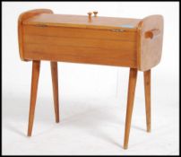 A retro 20th century sewing / work box having a tambour sliding lid raised on slender tapering