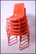 A set of six retro Robin Day style stacking chairs having a vibrant orange seat raised on orange