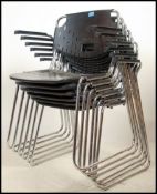 A set of contemporary modern Dallas chrome and black plastic stacking chairs raised on tubular