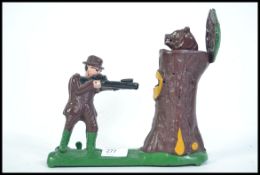 A novelty cast iron painted money box of an archer firing into a tree stump with hinged lid having