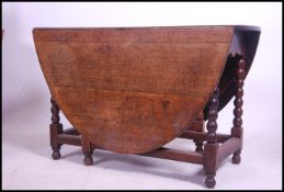 A 19th century carved country oak gate leg - drop leaf dining table raised on bobbin turned legs