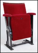 A vintage retro 20th century cinema seat having a cast metal frame with drop down seat. The seat pad