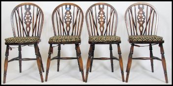 A set of 4 oak wheelback dining chairs being raised on turned legs united by stretchers having