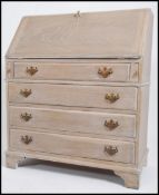 A vintage 20th century limed oak bureau having a fall front with leather scribe and fully